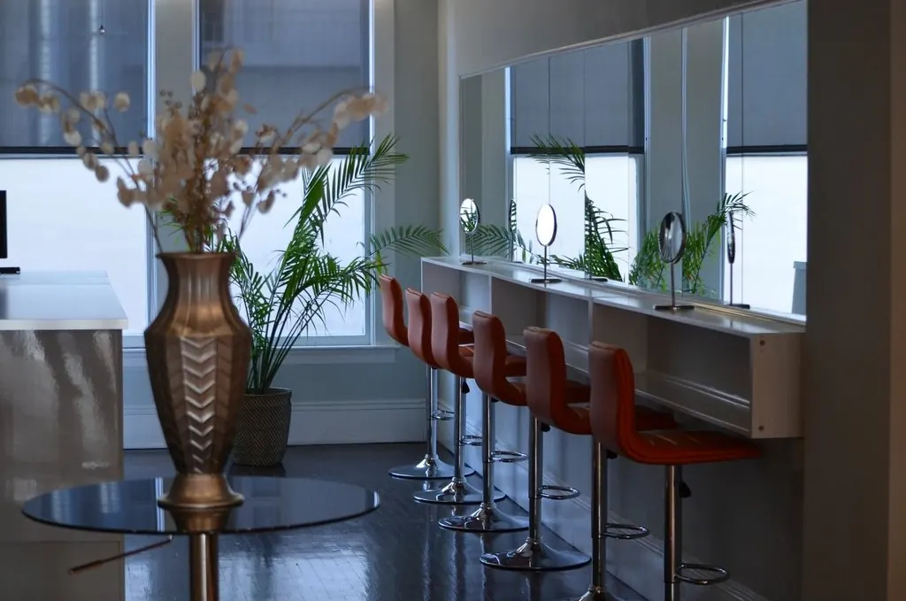 Het interieur van Salon Camille: spiegels op een rij met salonstoelen ervoor